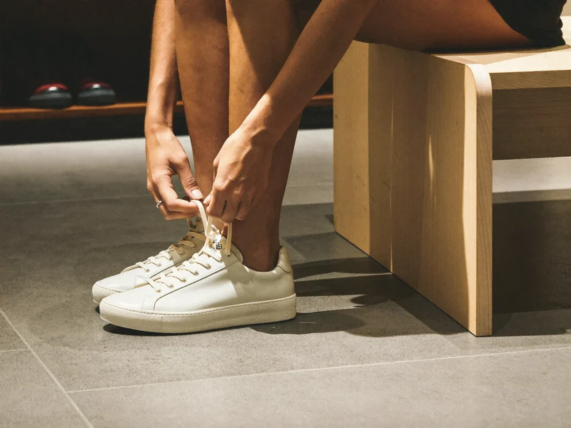 Fødder i sneakers på en lav prøvebænk, mens et snørebånd bindes, illustration